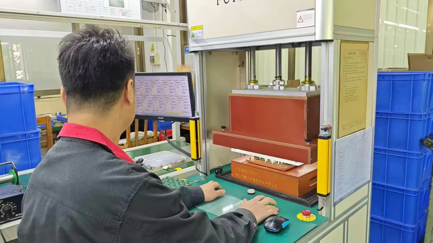 Technician running a hot bar soldering process on a control board with a process monitor alongside