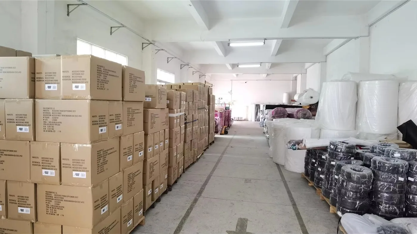 Cartons and coiled material stored along a warehouse aisle with racking